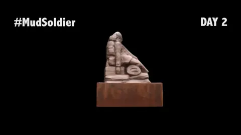 Escultura de arena y barro de un soldado sobre un pedestal, en un fotograma del registro de su deterioro.